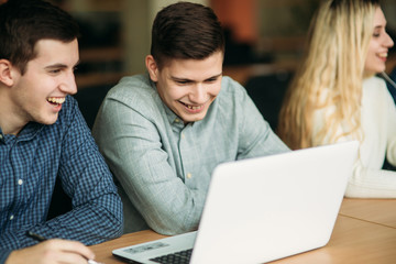 Group of college students studying in the school library, a girl and a boy are using a laptop and connecting to internet