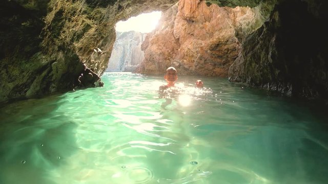 Happy young woman in bikini swimming in water cave near Ponza island coast sea in Italy