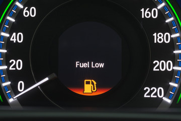 Close up empty Petrol, gasoline gauge dash board in car with digital warning sign of run out of fuel turn on on black background. Low level of fuel show on speedometer dashboard.Odometer Day