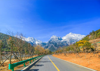 A road leads to the foot of the snowy mountain in the distance, in Lijiang, Yunlong, Yunnan, China