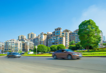 Naklejka premium Modern urban landscape, high-rise buildings, lush parks, fast driving of various cars on asphalt roads, in sunny summer