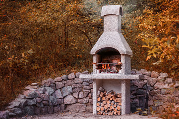 Stone garden oven for grill or barbeque is in a backyard at autumn season