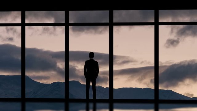 The man standing near panoramic windows on the cloud flow background. time lapse