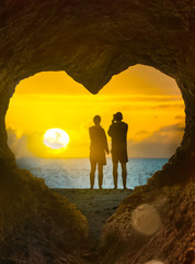 Paar am Strand von Fuerteventura schaut sich gemeinsam den Sonnenaufgang über dem Meer im Urlaub an 