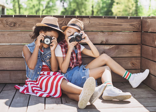 Beautiful little girls taking pictures with photocameras. Cute smilling happy girls playing outdoors