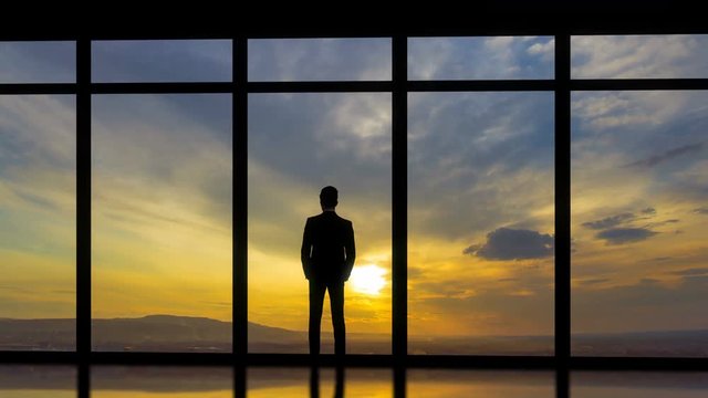 The man standing near windows on the sunset background. time lapse