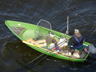 Fisher Man Fishing On Boat On Daugava River Under Bridge In Riga