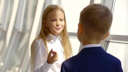 small school girl is flirting and chatting with her little friend boy, view on her pretty face - Powered by Adobe