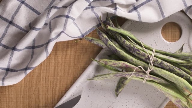 Heap of green beans on a rustic wooden table top view. Cutting board with green beans
