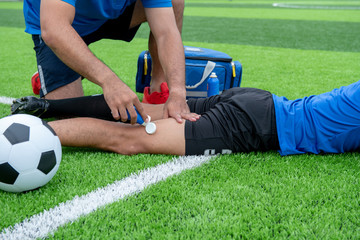 Naklejka premium Footballer wearing a blue shirt, black pants injured in the lawn during the race.