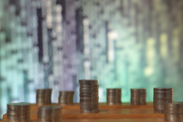 big coin piles in front of out of focus computer screen displayed blue green code matrix. online saving innovation idea.