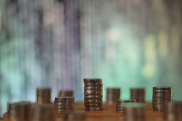 big coin piles in front of out of focus computer screen displayed blue green code matrix. online saving innovation idea.