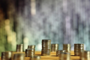 big coin piles in front of out of focus computer screen displayed blue green code matrix. online saving innovation idea.