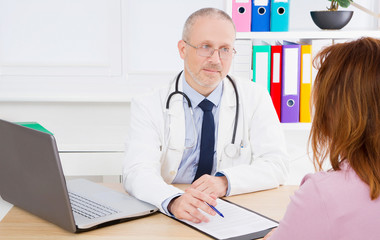 Doctor is talking with woman patient and sitting in medical office.Man in white uniform. Medical...