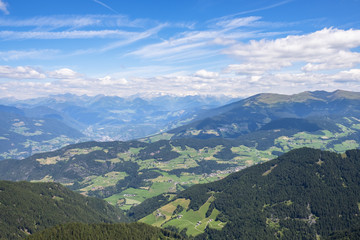 Aerial view of an Alp valley with fields and farms and mountain peaks