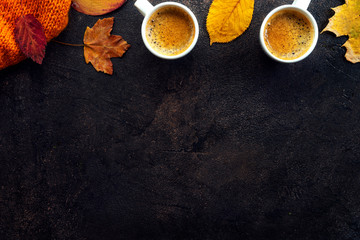 Top view of two cups of coffee around yellow leaves