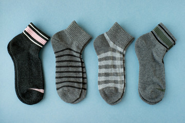Set of socks on a blue background. View from above. Warm clothing for the feet in the autumn and winter season. Classic dark and gray socks.