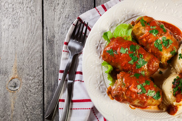 Stuffed cabbage with meat and rice served with boiled potatoes and tomato sauce