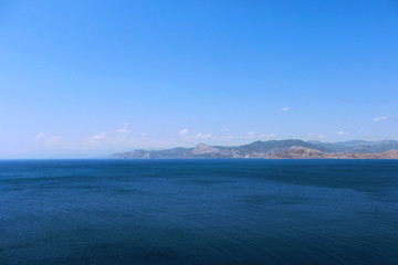 Panoramic view of Black sea with blue air. Black Sea, Crimea. Mountain relief disappearing on the horizon in a foggy haze on a hot summer day.