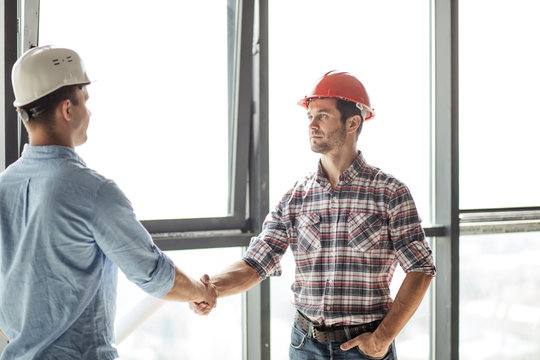 working partnership concept. architect is giving a hand to a n engineer to show his collaboration. close up portrait. builder has accepted the terms of a contract