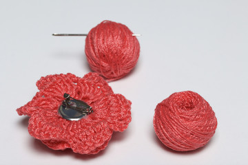 Ornaments made by own hands. On the table lies tangle of threads, a barrette and a knitted brooch...