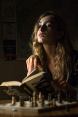 young woman posing and playing chess at dark room