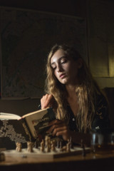 young woman posing and playing chess at dark room