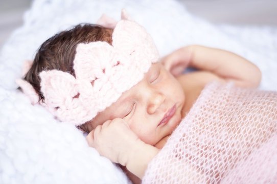 Sweet sleeping tiny newborn princess with a pink crown wrapped in a soft blanket. Cute newborn baby sleeping stock image.