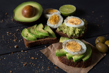 Avocado breakfast on black wood. Vegetarian Healthy Food Concept. Top view.