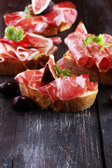 Sandwich with prosciutto or salami or crudo. Antipasti gourmet bruschetta snack.