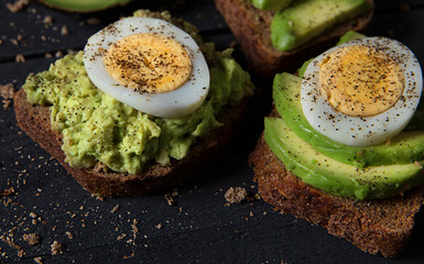 Avocado breakfast on black wood. Vegetarian Healthy Food Concept. Top view.