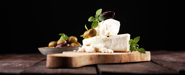 Greek cheese feta with herbs and olives on rustic table. - obrazy, fototapety, plakaty