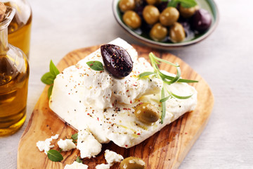 Greek cheese feta with herbs and olives on rustic table.