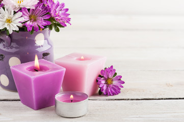 Fototapeta na wymiar Purple lit candles and pink garden flowers