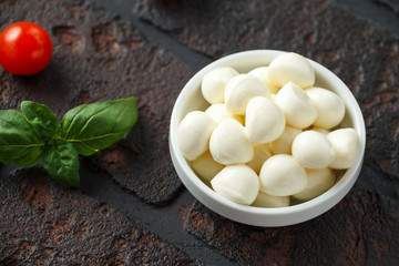 Fresh Italian Mozzarella cheese with cherry tomatoes and basil in white bowl