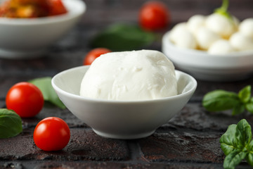 Fresh Italian Mozzarella cheese with cherry tomatoes and basil in white bowl