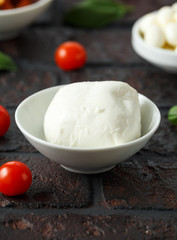 Fresh Italian Mozzarella cheese with cherry tomatoes and basil in white bowl