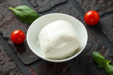 Fresh Italian Mozzarella cheese with cherry tomatoes and basil in white bowl