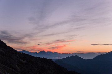 Obraz na płótnie Canvas Alpine Mountains Summits at Dawn with Crimson Clear Sky.