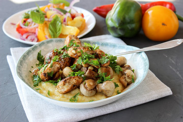 mashed potatoes with fried mushrooms and chicken on a side dish with tomatoes.