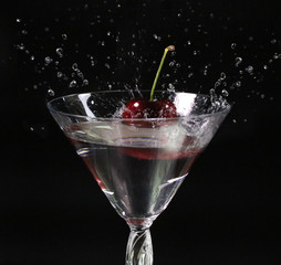 Cherry Fall in to glass of water splash on dark background