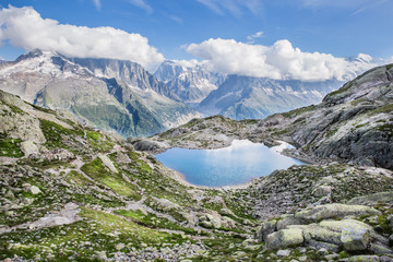 Naklejka na ściany i meble Alpine Lake and Snowy Mont-Blanc Mountains Range on a Sunny Summer Day