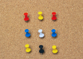 Clse-up, nine colored pinned button on a cork board