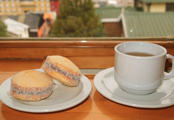Pair of Alfajores, Traditional Latin American Sweets and a Cup of Hot Tea Served on Wooden Table by the Window, Ushuaia, Argentina 