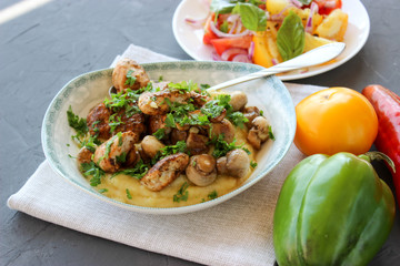 mashed potatoes with fried mushrooms and chicken on a side dish with tomatoes.