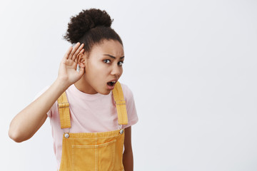 You say what repeat. Portrait of intense confused african-american woman with hair in bun, bending...