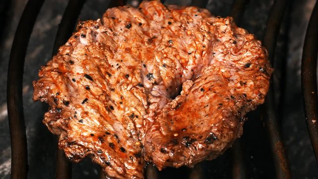 UHD shot of juicy Mexican style marinated beef steak on the grill with flames and smoke