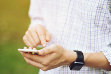 Close up of a business man hand holding stand using mobile smart phone Bluetooth connect wrist watch outdoor cellphone in public park. Technology Connection signal concept.