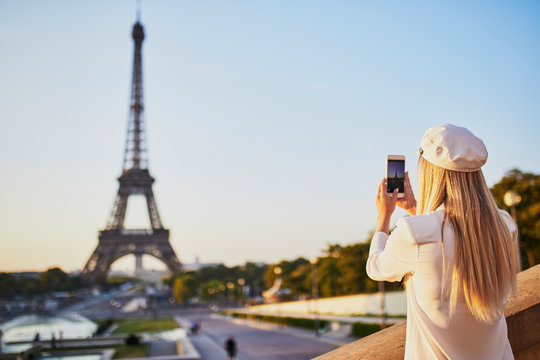 woman with long blond hair taking photo of the Eiffel tower