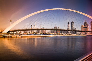 Naklejka premium DUBAI, UAE - FEBRUARY 2018: Colorful sunset over Dubai Downtown skyscrapers and the newly built Tolerance bridge as viewed from the Dubai water canal.